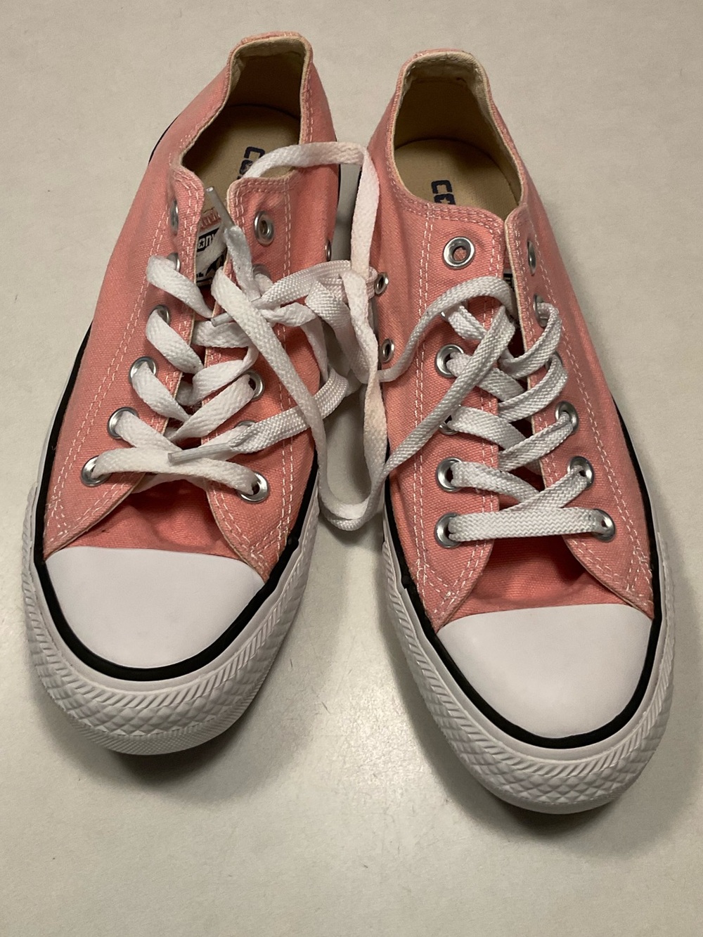 Converse Chuck Taylor All Star low-top sneakers in a light pink canvas material.